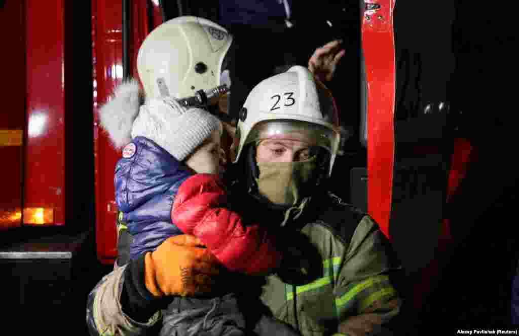 Рятувальник несе дитину, поки місцеві жителі виходять із вантажівки під час екстреної евакуації із затопленої вулиці у Євпаторії