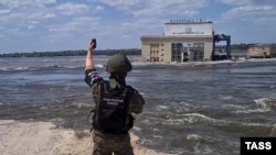 Представник окупаційних військ Росії на лівому березі Дніпра стоїть навпроти знищеної Каховської ГЕС, Україна, червень 2023 року