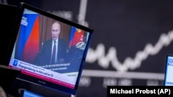 Президент Росії Володимир Путін на екрані телевізора на тлі ринкових графіків. Ілюстративне фото