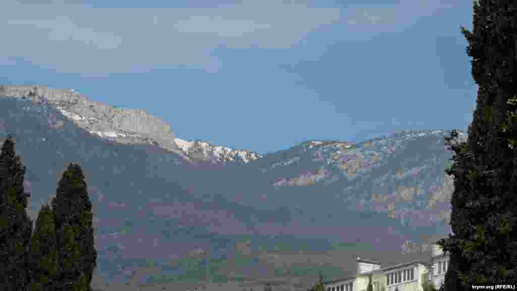 Снігові верхівки гір нависають над маленьким курортним селищем, захищаючи його від вітру