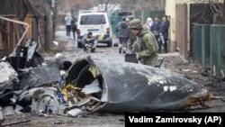 Український військовослужбовець оглядає частини збитого літака під час повномасштабного вторгнення Росії в Україну. Київ, 25 лютого 2022 року